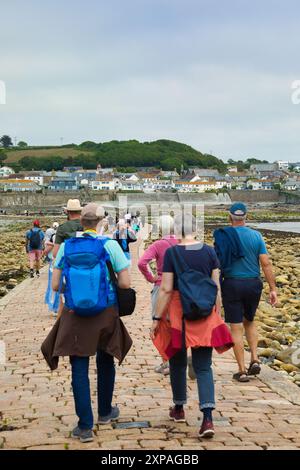 Touristen wandern auf dem Granitdamm von Marazion zur Tidal Island St. Michaels's Mount, Marazion, Cornwall, England Stockfoto