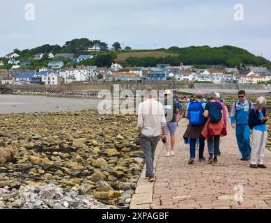 Touristen wandern auf dem Granitdamm von Marazion zur Tidal Island St. Michaels's Mount, Marazion, Cornwall, England Stockfoto