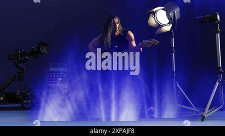 Ein männlicher Rockstar steht auf der Bühne und spielt seine elektrische Gitarre in einem Konzertsaal. Stockfoto