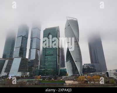 Wolkenkratzer mit ihren Spitzen, die von Nebel an einem bewölkten Tag verdeckt sind. Städtisches Stadtbild mit modernen Hochhäusern - Moskau, Russland, 09. November 2022 Stockfoto
