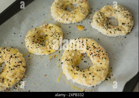 Hausgemachte Hüttenkäse-Bagels auf Pergamentpapier, fertig zum Backen Stockfoto