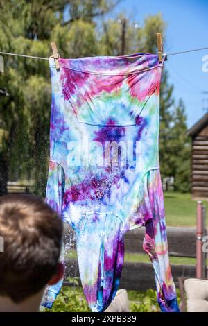 Junge Spülen einen farbenfrohen Hoodie, der an einer Wäscheleine hängt Stockfoto