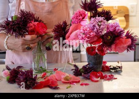 Frau, die einen Blumenstrauß in einer Vase auf einer Küchenzeile arrangiert Stockfoto