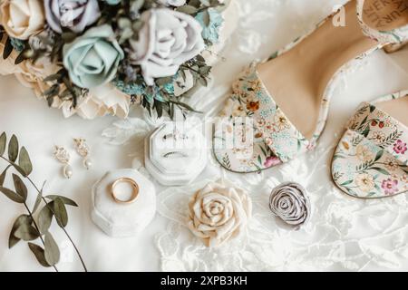 Brautaccessoires wie Ringe, Blumenstrauß und Schuhe mit Blumenmuster Stockfoto