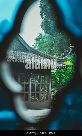 Blick auf einen chinesischen Gartenpavillon durch einen blau gemusterten Rahmen. Stockfoto