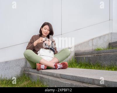 Die Frau gehäkelt draußen. Ruhige Freizeit für Frauen im städtischen Park. Anti-Stress-Hobby. Stockfoto