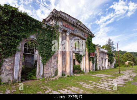 Verlassener Bahnhof in der Stadt Tkvarcheli, Abchasien. Alte Bauruinen, die im Sommer von Gras und Efeu bewachsen sind. Konzept von Krieg, Grunge, Architektur, Stockfoto