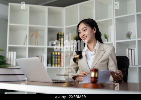 Professionelle Anwältin, die am Schreibtisch in einem modernen Büro mit Rechtsdokumenten und Laptop arbeitet Stockfoto