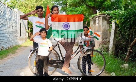 Kinder mit Familienmitgliedern tragen T-Shirt mit indischer Flagge und halten, winken oder laufen mit Tricolor mit Grün im Hintergrund, feiern Stockfoto