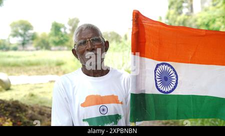 Kinder mit Familienmitgliedern tragen T-Shirt mit indischer Flagge und halten, winken oder laufen mit Tricolor mit Grün im Hintergrund, feiern Stockfoto