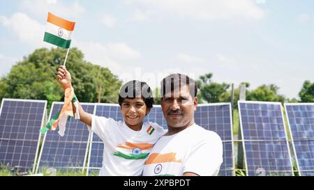 Kinder mit Familienmitgliedern tragen T-Shirt mit indischer Flagge und halten, winken oder laufen mit Tricolor mit Grün im Hintergrund, feiern Stockfoto