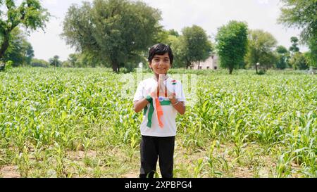 Kinder mit Familienmitgliedern tragen T-Shirt mit indischer Flagge und halten, winken oder laufen mit Tricolor mit Grün im Hintergrund, feiern Stockfoto