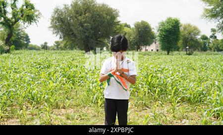 Kinder mit Familienmitgliedern tragen T-Shirt mit indischer Flagge und halten, winken oder laufen mit Tricolor mit Grün im Hintergrund, feiern Stockfoto