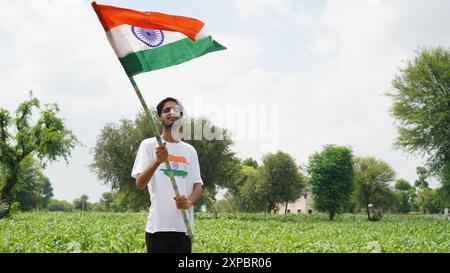 Kinder mit Familienmitgliedern tragen T-Shirt mit indischer Flagge und halten, winken oder laufen mit Tricolor mit Grün im Hintergrund, feiern Stockfoto