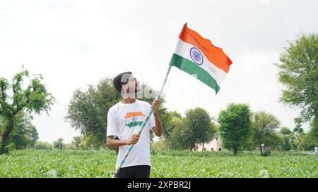 Kinder mit Familienmitgliedern tragen T-Shirt mit indischer Flagge und halten, winken oder laufen mit Tricolor mit Grün im Hintergrund, feiern Stockfoto