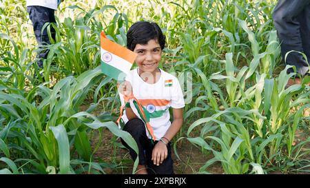 Kinder mit Familienmitgliedern tragen T-Shirt mit indischer Flagge und halten, winken oder laufen mit Tricolor mit Grün im Hintergrund, feiern Stockfoto