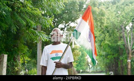 Kinder mit Familienmitgliedern tragen T-Shirt mit indischer Flagge und halten, winken oder laufen mit Tricolor mit Grün im Hintergrund, feiern Stockfoto