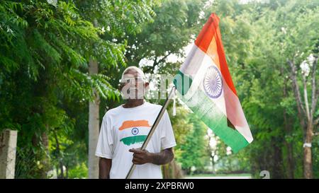 Kinder mit Familienmitgliedern tragen T-Shirt mit indischer Flagge und halten, winken oder laufen mit Tricolor mit Grün im Hintergrund, feiern Stockfoto