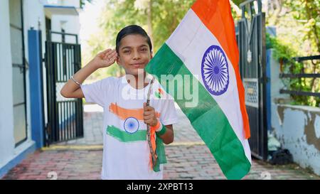 Kinder mit Familienmitgliedern tragen T-Shirt mit indischer Flagge und halten, winken oder laufen mit Tricolor mit Grün im Hintergrund, feiern Stockfoto
