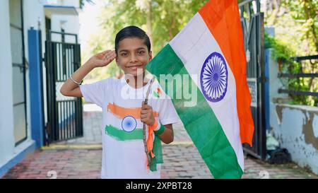 Kinder mit Familienmitgliedern tragen T-Shirt mit indischer Flagge und halten, winken oder laufen mit Tricolor mit Grün im Hintergrund, feiern Stockfoto