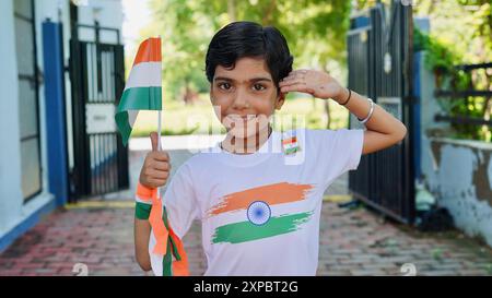 Kinder mit Familienmitgliedern tragen T-Shirt mit indischer Flagge und halten, winken oder laufen mit Tricolor mit Grün im Hintergrund, feiern Stockfoto