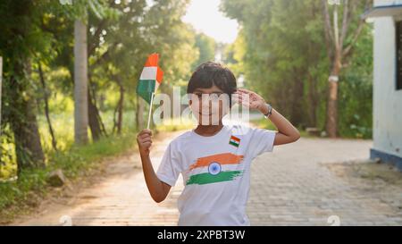 Kinder mit Familienmitgliedern tragen T-Shirt mit indischer Flagge und halten, winken oder laufen mit Tricolor mit Grün im Hintergrund, feiern Stockfoto