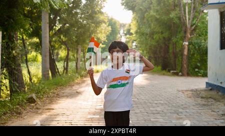 Kinder mit Familienmitgliedern tragen T-Shirt mit indischer Flagge und halten, winken oder laufen mit Tricolor mit Grün im Hintergrund, feiern Stockfoto