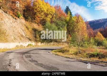 Asphaltstraße in den Bergen im Herbst. Wald auf dem Hügel im Herbstlaub. Sonniges Wetter. Roadtrip durch die Landschaft der ukraine Stockfoto
