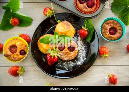 Süße Quark-Muffins mit Erdbeerfüllung, auf einem Teller auf einem Holztisch. Stockfoto