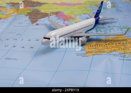 Spielzeugflugzeug auf der Karte von Australien und Indischem Ozean. Miniatur eines Passagierflugzeugs, das auf Weltkarte fliegt. Stockfoto