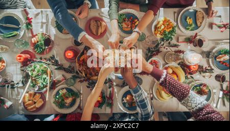 Familie und Freunde treffen sich zu Hause zu einem traditionellen Weihnachtsessen mit einem Truthahnbraten. Von oben nach unten sehen Sie, wie die Menschen Champagnergläser hochheben und einen gemeinsamen Feiertag feiern Stockfoto