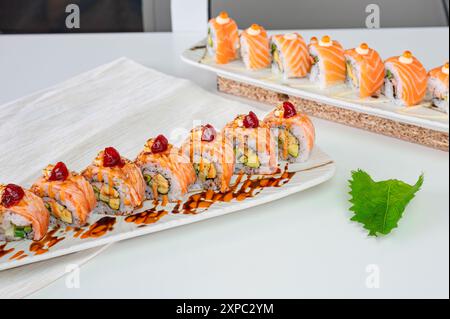 Keramiktablett mit verschiedenen Lachs-Sushi-Brötchen mit Gemüse, appetitliche Mahlzeit im japanischen Restaurant Stockfoto