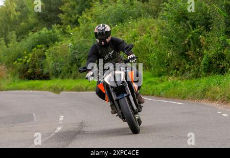 Whittlebury, Norhants, Großbritannien - 4. August 2024. Mann, der auf einer britischen Landstraße ein 2020 orangefarbenes KTM 1290 Superduke R20 Motorrad fährt Stockfoto