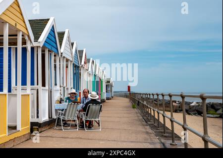 Leute, die Cocktails trinken, sitzen vor einer Strandhütte in Southwold, Suffolk, Großbritannien. Konzepturlaub, englischer Sommer, englischer Urlaub, Meer. Stockfoto