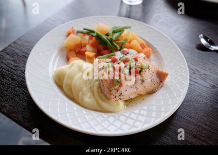 Gegrilltes Lachssteak mit Kartoffelpüree und Gemüse auf weißem Hauptgericht im Restaurant Stockfoto