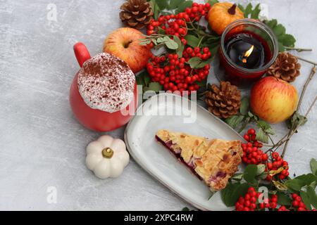 Stillleben im Herbst mit einer Tasse heißem Kaffee, Heidelbeerkuchen, Kerze, Kürbissen und vogelbeeren. Süßer hausgemachter Kuchen auf einem Tisch. Stockfoto