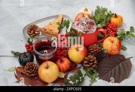 Ein Stück Heidelbeerkuchen auf einem Teller mit Herbstdekorationen, Kerzen und roten Blumen. Hellgrauer Hintergrund mit Kopierraum. Gemütliches Herbstessen. Stockfoto