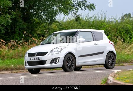 Whittlebury, Norhants, Großbritannien - 4. August 2024. 2016 weißes Suzuki Swift Fließheck Auto, das auf einer britischen Landstraße fährt Stockfoto