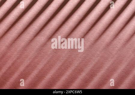 Abstrakter pastellrosa Hintergrund mit diagonalen Linien, die von Schatten und Lichtern gezeichnet werden. Stockfoto