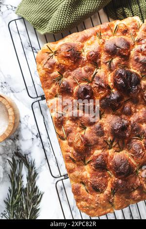 Ein köstliches und knuspriges Focaccia-Brot, garniert mit Rosmarin- und Salzflocken, kühlt auf einem Gitter. Stockfoto