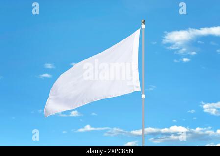 Weiße Flagge flattert an einem sonnigen Tag im Wind. Ideal für Mockups, das Hinzufügen von Designs oder nationale Flaggen. Klarer blauer Himmel im Hintergrund Stockfoto