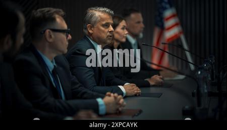 Männlicher Vertreter der Kaukasischen Organisation, der auf der Wirtschaftskonferenz spricht. Leiter der Delegation der Vereinigten Staaten bei einer Rede auf einem internationalen politischen Gipfel. Verschiedene Teilnehmer Hören Zu. Stockfoto