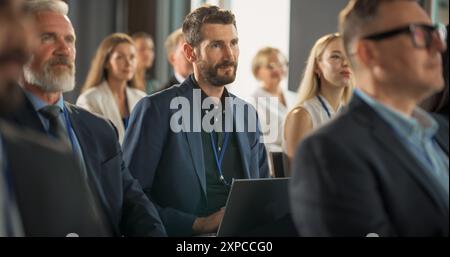 Kaukasier sitzt in einem überfüllten Auditorium auf einer internationalen Konferenz. Professioneller Anwender, Der Einen Laptop Verwendet. Innovative Präsentation: Technologie, Wissenschaft, Gesundheit, Achtsamkeit, Wirtschaft. Stockfoto