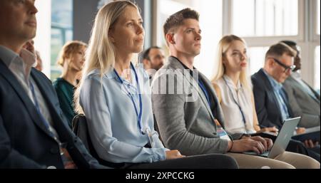 Junge Psychologin bei einem Internationalen Seminar zur kognitiven Verhaltenstherapie. Die kaukasische Frau konzentriert sich auf die Moderatorin. Psychotherapie-Profi sitzen im überfüllten Raum im Trainingsprogramm. Stockfoto