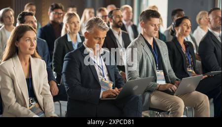 Kaukasischer männlicher CEO sitzt in einer Vielzahl von Wirtschaftsführern auf dem Internationalen Wirtschaftsforum. Erfolgreicher Geschäftsmann, Der Präsentationen Über Umwelt, Entwicklungsländer Und Technologie Anhört. Stockfoto