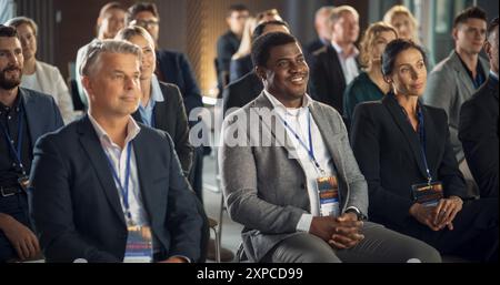 Verschiedene Geschäftsleute Sitzen Bei Der Internationalen Technologiekonferenz Im Publikum. Unternehmerinnen Und Unternehmer Hören Keynote Von Startup Company Mit Innovativem Produkt Oder Service. Stockfoto