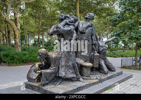 New York, NY, USA - 4. August 2023: Einwanderungsdenkmal von Luis Sanguino im Battery Park. Grünes Laub hinten Stockfoto