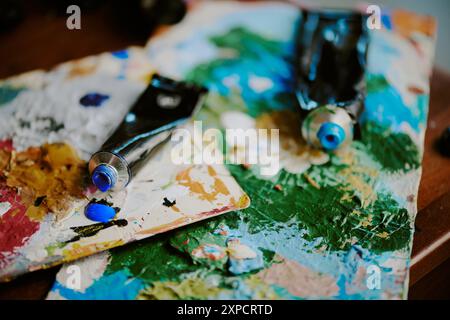 Nahaufnahme geöffneter Acrylfarben-Tuben, die auf Paletten am Arbeitsplatz des Künstlers liegen Stockfoto