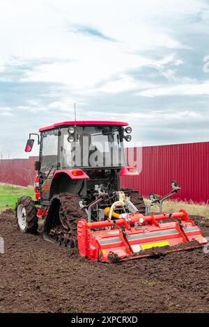 Ein Minitraktor mit einer Fräsmaschine pflügt an einem Herbsttag auf einem landwirtschaftlichen Feld den Boden. Stockfoto