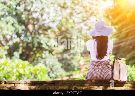 Eine junge Reisende sitzt am Straßenrand, um die Karte und das Ziel zu sehen, das sie erreichen möchte. Das Mädchen saß allein am Straßenrand Stockfoto